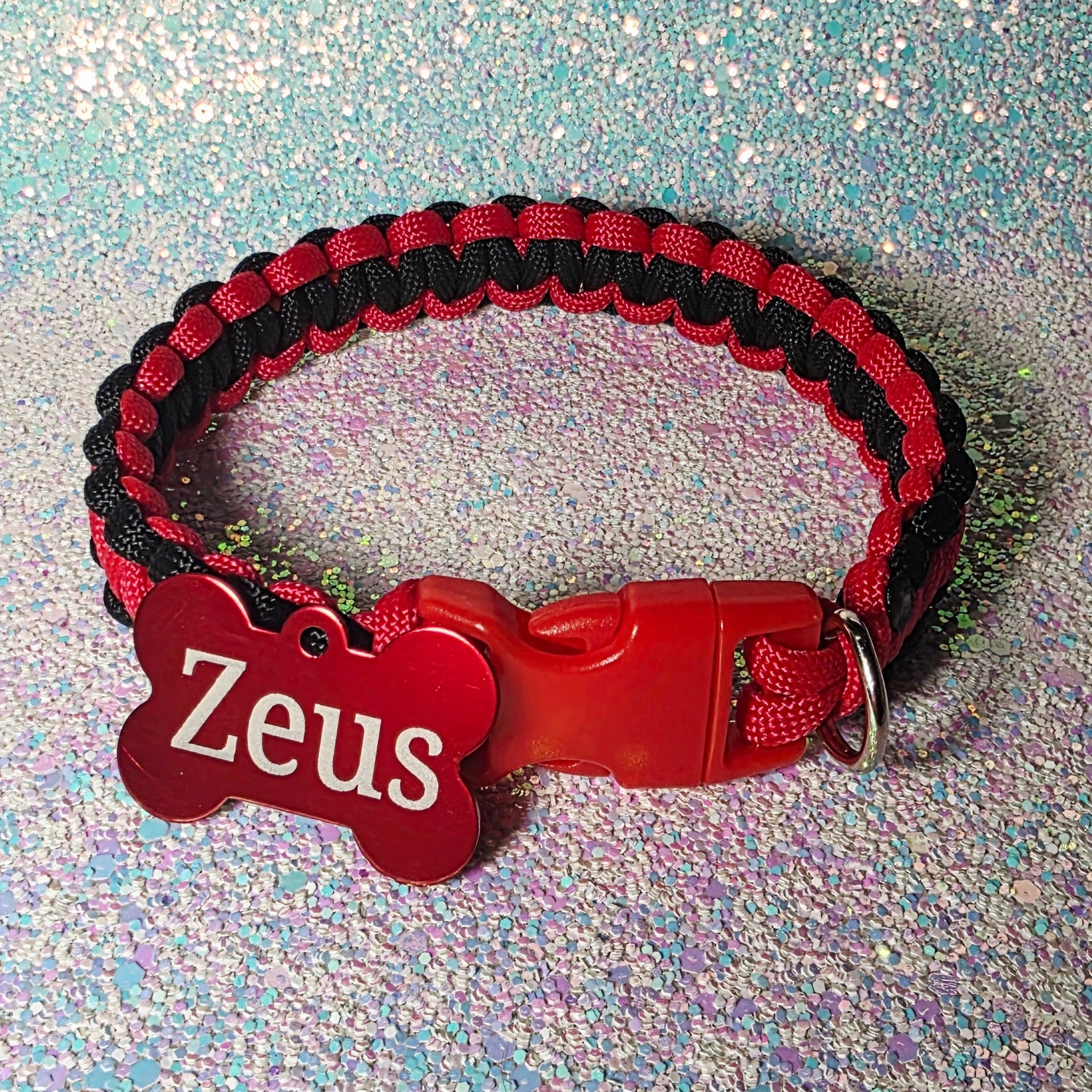 Red and black braided dog collar with a red tag on a glittery blue background